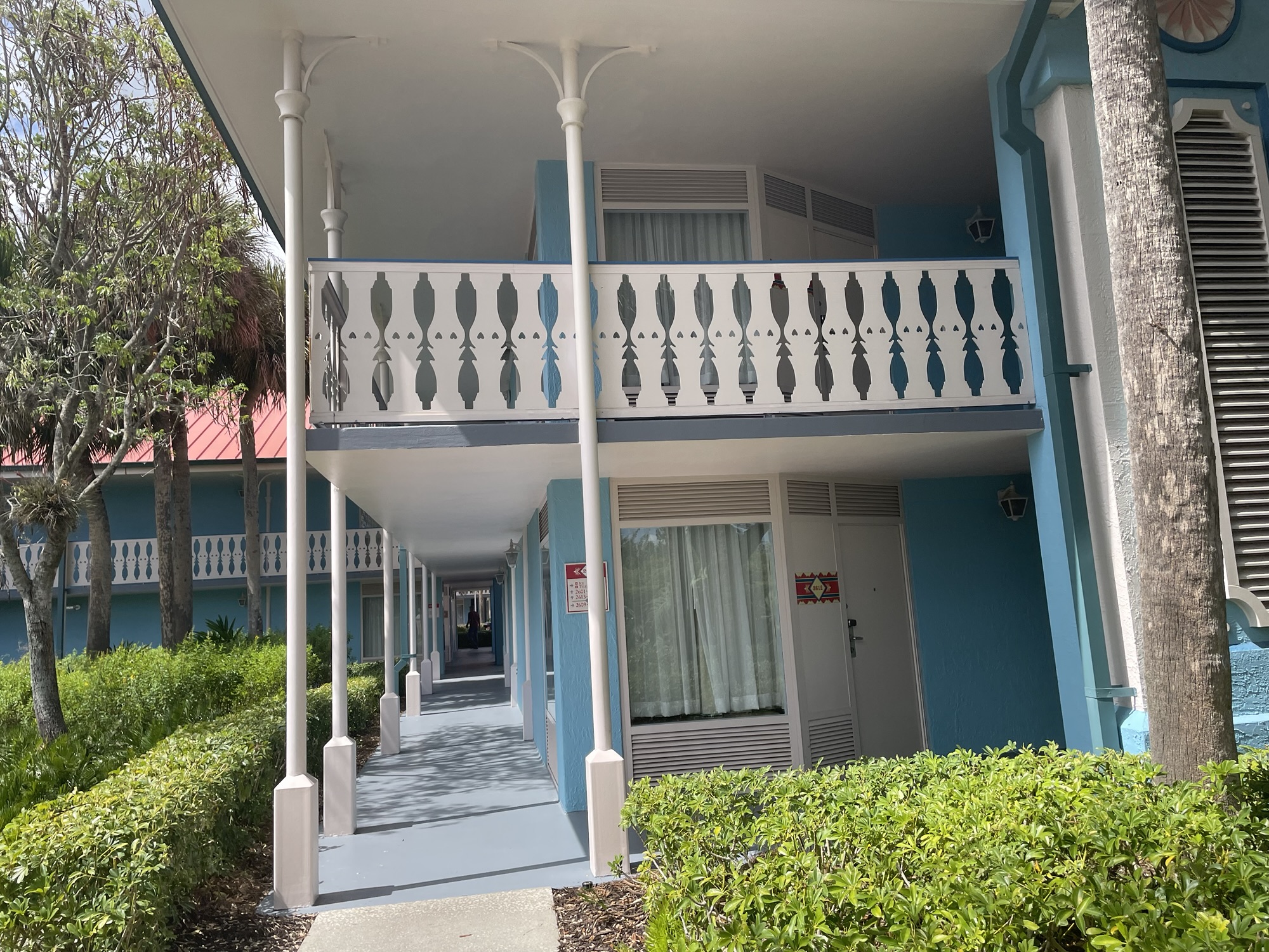 A look at outside walkways at Martinique section of Disney's World's Caribbean Beach Resort. Light blue exterior with white railing. Two stories.